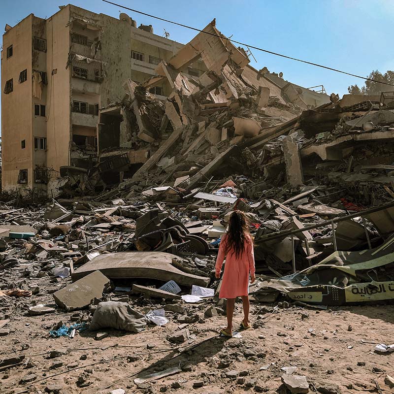 In Gaza, a young girl stands amidst the building rubble that was destroyed by Israeli airstrikes.